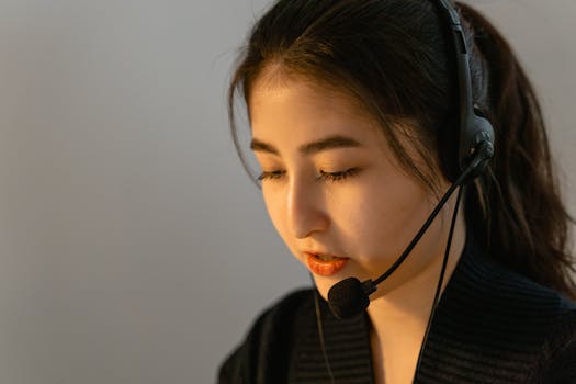 Home Focused young woman in headset working in customer support, speaking attentively.